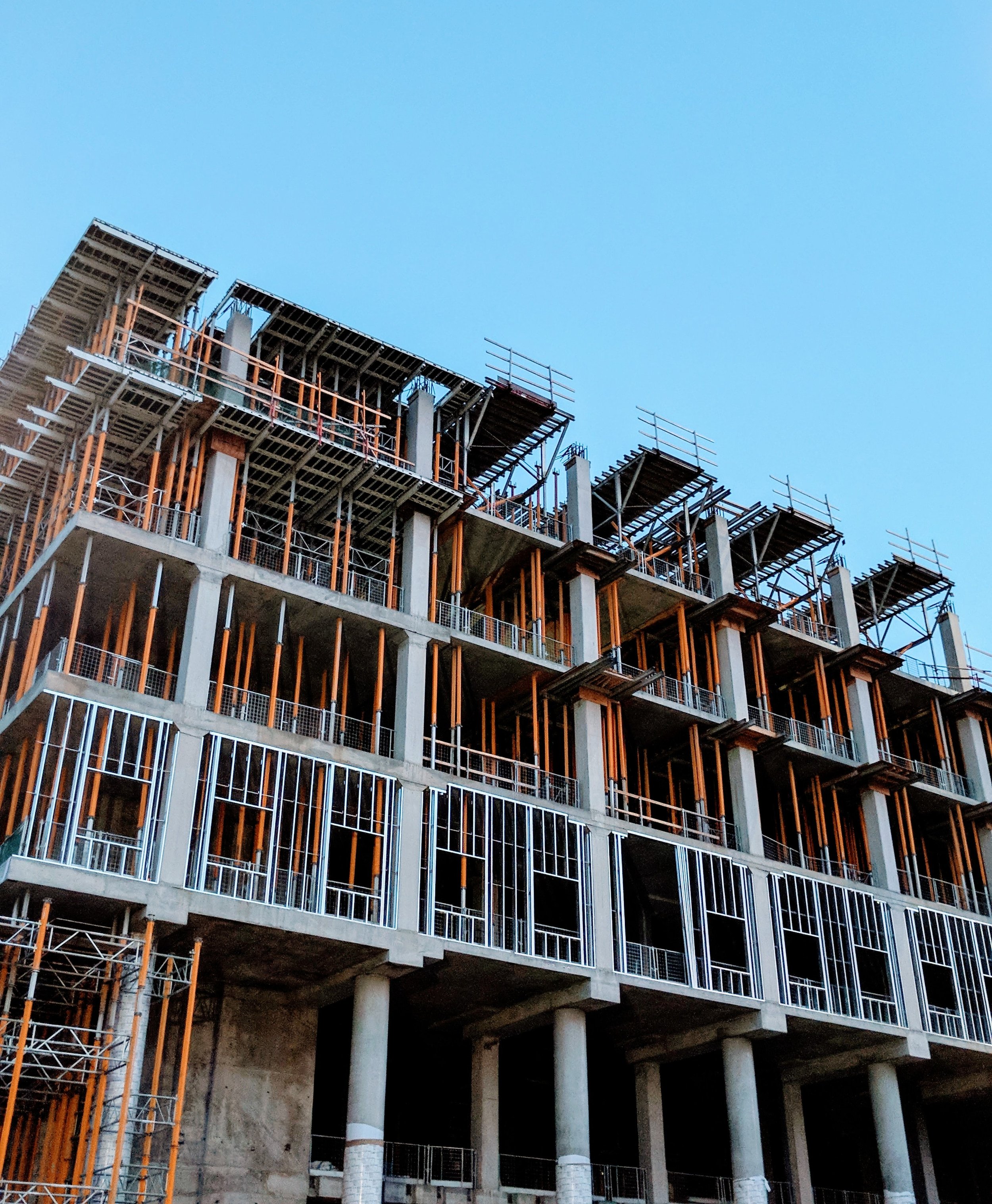 Multistory concrete building frame under construction, with shoring posts and scaffolding