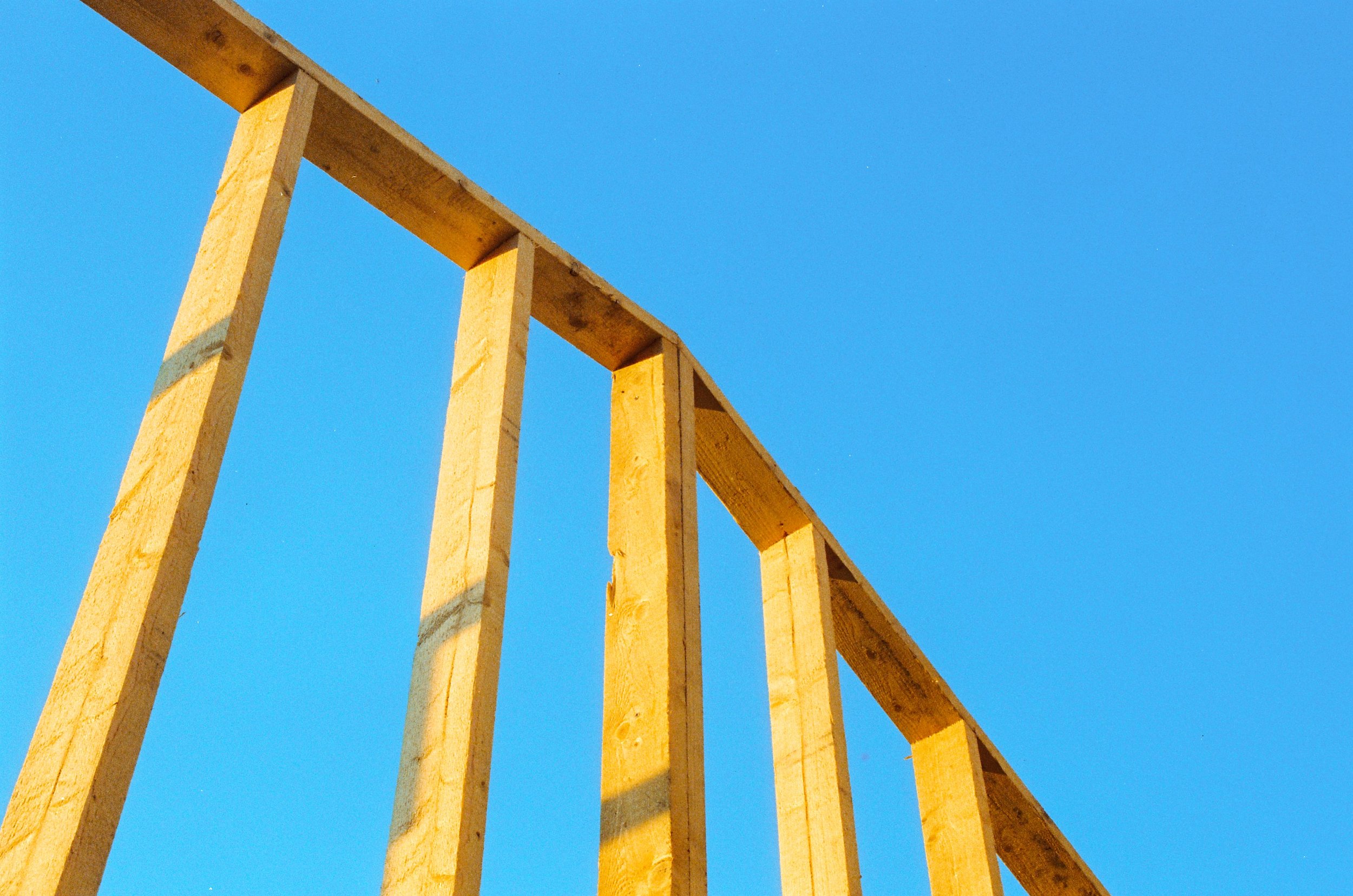 Wood stud framing of a building under construction against a clear sky