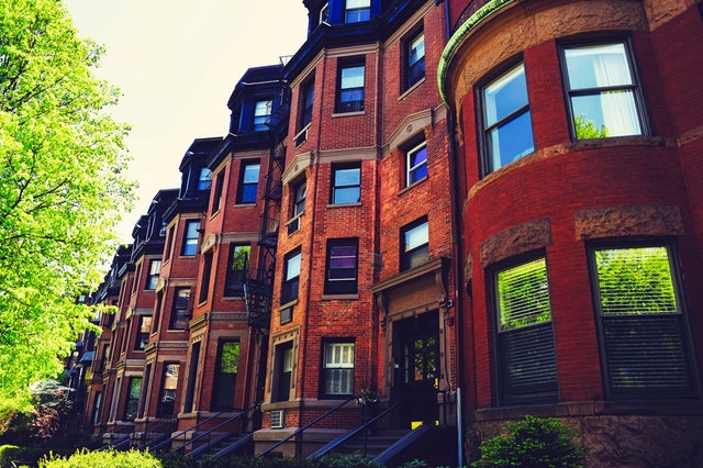 Row of brick apartment buildings with bay windows on a tree-lined street